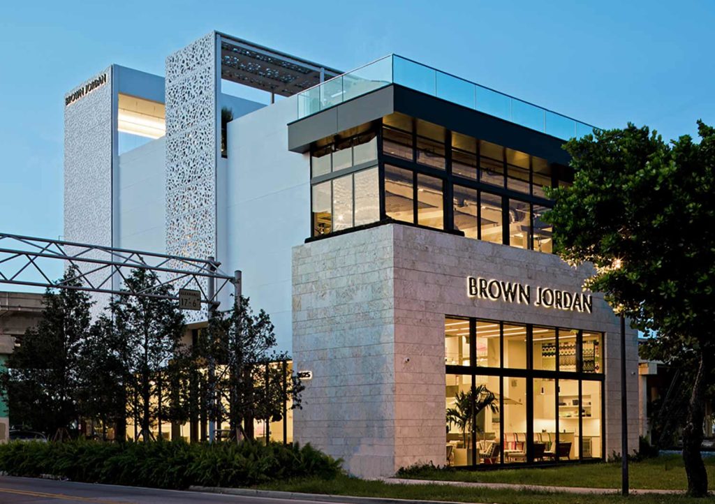 This flagship retail project’s concept and materiality were inspired by the Dade County pine forest and coral-rock bluffs that once blanketed the project site. Less than 2 percent of this endangered pine rockland still survives.

The building is composed of volumes that appear to rise from the park green at its southern edge. The first plate is clad in locally sourced Florida keystone, the same material oolitic limestone quarried locally from the coral bluffs that marked this coastal area. The taller, alternating plates are clad in panels that recall the dappling of daylight through the pine branches. These panels are fabricated from high strength, fiber-reinforced concrete. The interior paneling, stair treads, and cabinetry are made of reclaimed Dade County pine, salvaged from a nearby building during the process of demolition. 

As the flagship for an outdoor furniture line, it was especially important to showcase indoor/outdoor living for our subtropical climate. The design features a rooftop garden and exhibit areas that are open to the sky, with views of Downtown Miami, the Design District, and Biscayne Bay. The ground floor includes a modern take on a “Florida Room” that opens to a nearby park. All the spaces are day-lit and use local materials for a truly Floridian store.